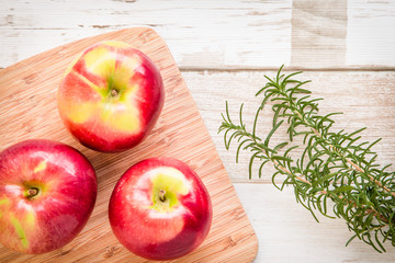 Healthy food: red apples and rosemary on wooden table