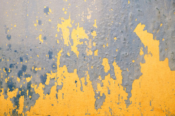 Wall in bad condition with old yellow and blue paint inside house in process of repair as background closeup