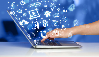 Hand writing on notebook computer with media icons and symbols