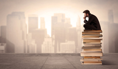 Man sitting on books in the city