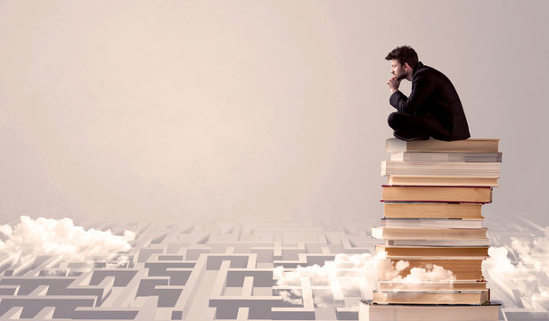 Businessman sitting on books in labirynth