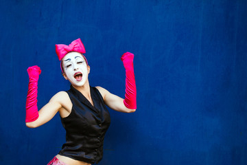 Mime portrait near a blue wall.