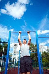 Fototapeta premium Muscular man doing pull-ups on horizontal bar