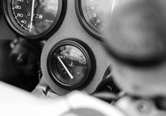 Temperature gauge on sport motorcycle. Photographed outdoor. Black and white photo.