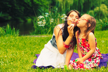 Fototapeta premium Mother and child blowing soap bubbles outdoor.