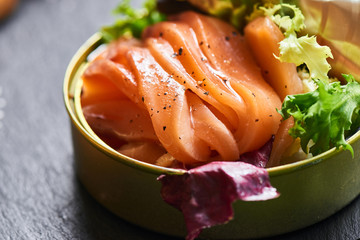 Poorly salted salmon served in a tin on a stone plaque closeup