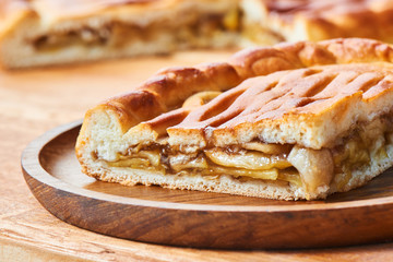 A piece of pie with a filling of apples on a wooden plate