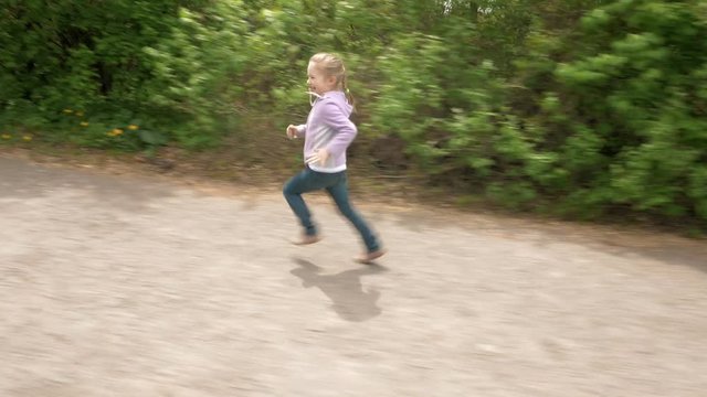 Playful little 5 years child girl runs on outdoor game laughs and smiles. Carefree childhood summer and happiness concept. 4K UHD video footage.