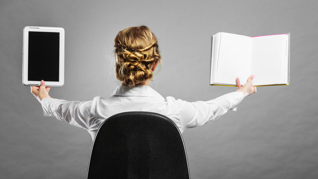 Woman holding traditional book and e-book reader