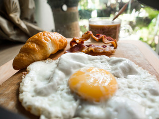 Breakfast with croissants, bacon, eggs Claire hot coffee on a wo