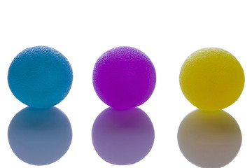 Squish exercise balls for carpal tunnel wrist strengthening and after stroke CVA hand strengthening exercises. Soft, medium and firm strength on balls isolated with reflection on table.