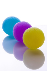 Squish exercise balls for carpal tunnel wrist strengthening and after stroke CVA hand strengthening exercises. Soft, medium and firm strength on balls isolated with reflection on table.