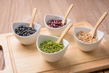 four colored beans  in ceramic bowl on wood block