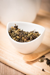  dry tea leaf in ceramic bowl wit whith pot on wood background
