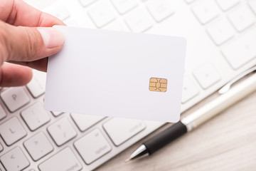 hand holding a white credit card and typing. On-line shopping on