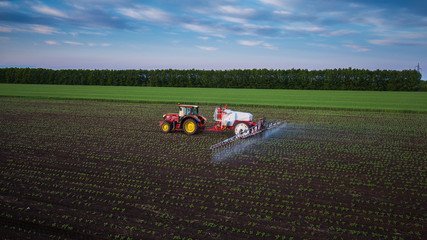 Obraz premium Tractor spraying field at spring