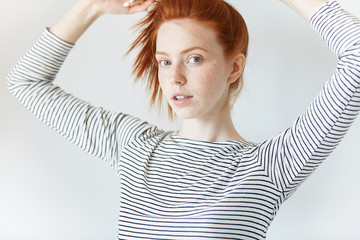 Cropped shot of hipster teenage girl with freckles looking at the camera with coquettish...