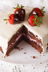 Beautiful chocolate cake with white icing and strawberries close-up. vertical
