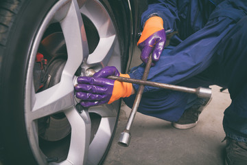 Car mechanic changing tire in the service.