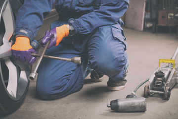 Car mechanic changing tire in the service.