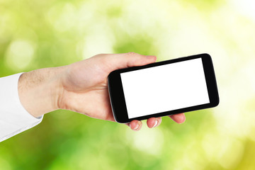 Hand shows mobile smart phone, nature blurred background