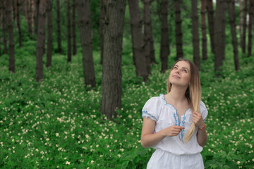 Beautiful young girl close-up in a white shirt, against a background of green forest