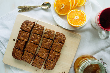 Chocolate brownie, orange and spoons on table