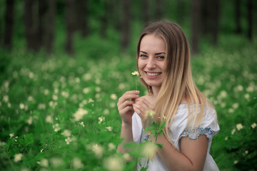 Fototapeta premium Beautiful young girl close-up in a white shirt, against a background of green forest