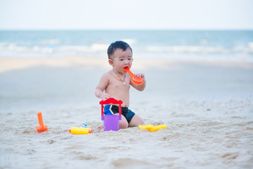 Little Asian boy 1 year old playing sand on the beach