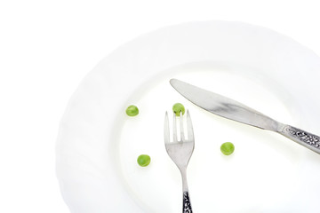 Fresh green peas on plate with fork and knife closeup, on white background