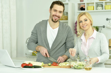 Obraz na płótnie Canvas happy couple cooking in kitchen
