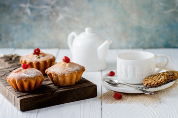 Tasty muffins with raisins and dried cherry on a white wooden table
