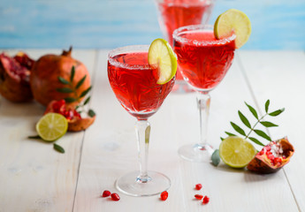 Glasses of garnet juice with lime, on white wooden background
