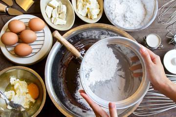 Hand Sift flour, prepare for cooking Chocolate brownie cake at bakery, Top view