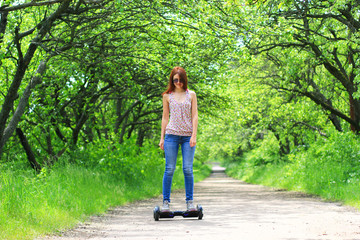 young woman riding electrical scooter in the park - personal eco transport, hoverboard, gyro scooter, smart balance wheel