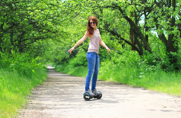 young woman riding electrical scooter in the park - personal eco transport, hoverboard, gyro scooter, smart balance wheel