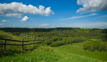 wooden fence in middle of the green hills
