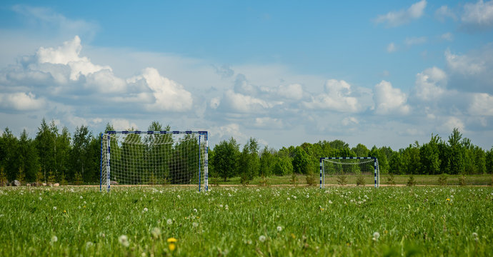 football goal in field on background of forest and sky