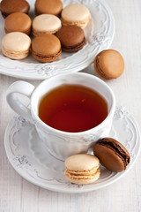 Colorful French macaroons and cup of tea on rustic wooden background