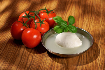 Mozzarella, tomatoes, basil, composition on a wooden table