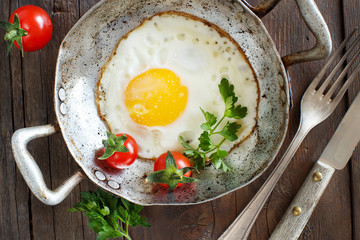 Fried egg with tomatoes and herbs n a old frying pan