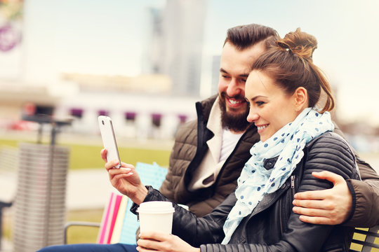 Young couple with shopping bags and smartphone