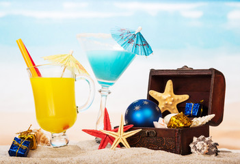 Cocktail, orange juice, starfish, treasure in  sand against the sea.