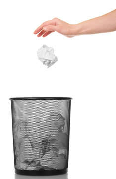 Hand throwing crumpled paper into metal basket isolated on white.