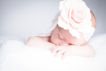 Obraz na płótnie Canvas Newborn baby with headband on the head lying on blanket. Sleepy newborn baby.