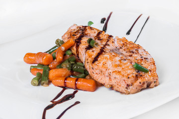 Grilled salmon with asparagus, carrots and sauce. Isolated dish on a white background