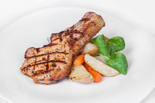Grilled beef rib steak with vegetables. Isolated dish on a white background