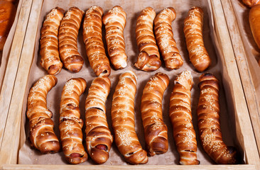 Hot dog with sesame seeds on shelf in Bakery shop. Pastries and bread in a bakery