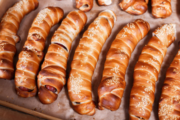 Hot dog with sesame seeds on shelf in Bakery shop. Pastries and bread in a bakery