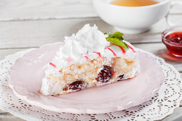 Tasty Cake with cream mascarpone and cherries on plate, on a light wooden background. Selective focus